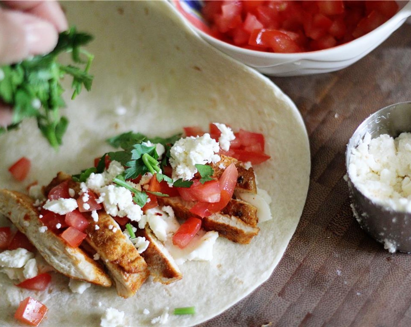 step 3 Place tortillas on a flat surface; divide the chicken, Tomato (1), Shredded Mozzarella Cheese (1/2 cup), Feta Cheese (1/3 cup), and Fresh Parsley (1/3 cup) between both tortillas.