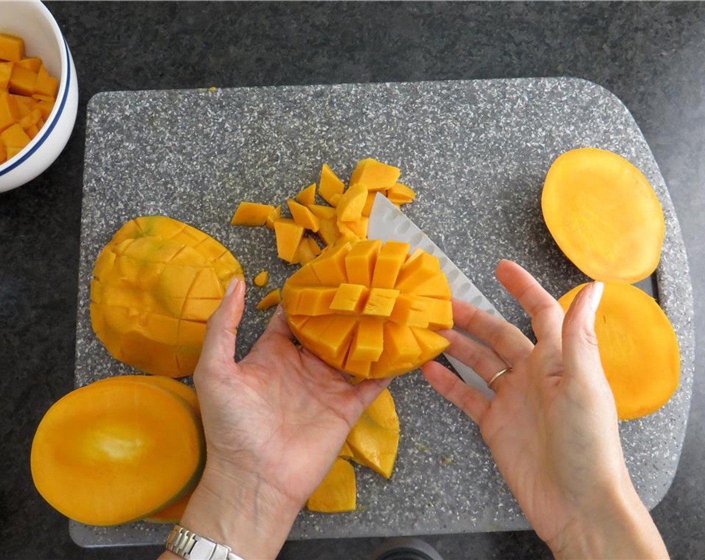 step 2 With a sharp knife, slice the mangoes vertically along either side of the pit, so you have two disc shaped slices. Score the mango flesh in a diamond pattern, and push the skin side out to expose the flesh. Slice flesh away from skin.