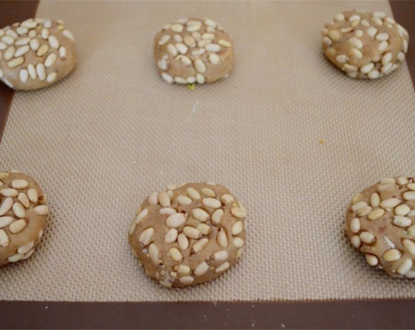 step 6 Transfer the dough to the lined sheet, press it down into a disk, and repeat until you have a dozen cookies on the tray. Bake the spiced pignoli cookies for about 20 minutes, until they are golden and baked through.