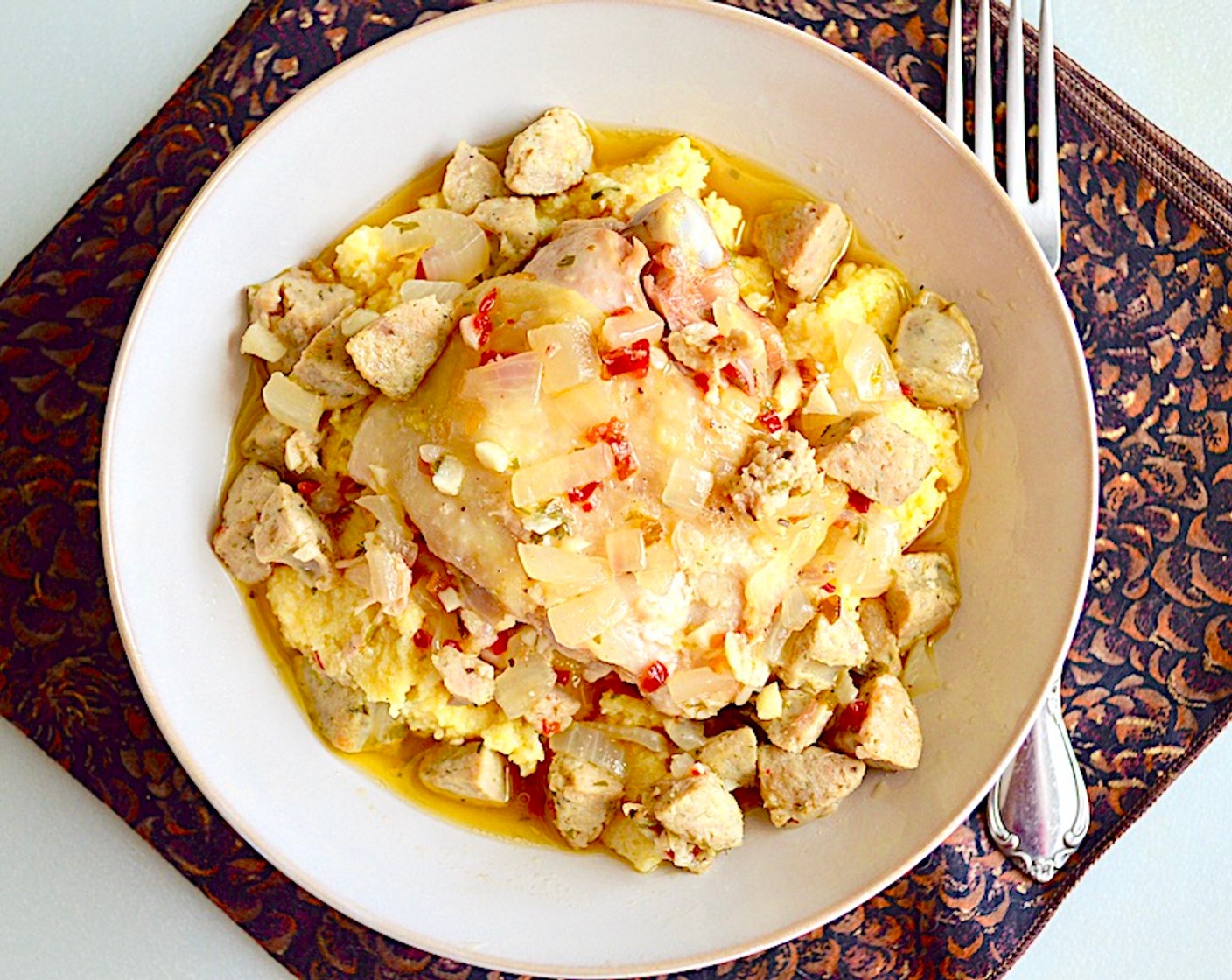 step 9 Scoop a generous helping of the polenta into a bowl and top it with one of the chicken thighs. Then ladle a couple of big scoops of the sausage and broth on top to complete the plating. Serve immediately and enjoy!