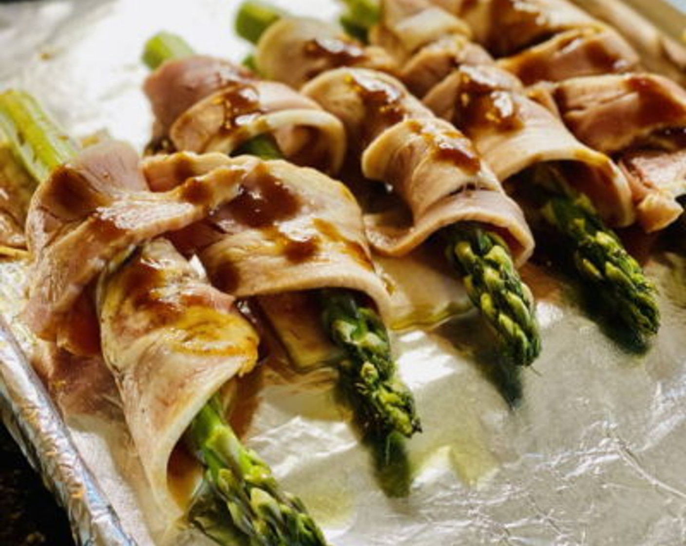 step 3 Lay the Bacon (6 slices) on a tray, and brush with half the Maple Barbecue Sauce (2 Tbsp). Then take a slice of bacon and wrap it around one of the asparagus spears, winding it around to cover the entire spear. Brush with the remaining Barbeque Sauce after wrapping the asparagus.

Repeat this process with the remaining asparagus spears and the place back onto the foil lined baking tray.