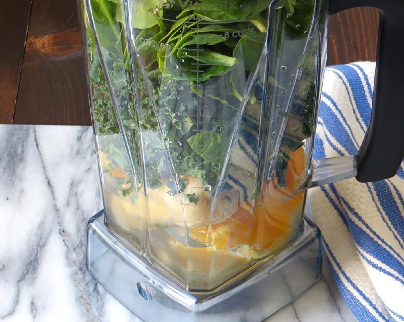 step 2 To your blender, add the orange, banana, Kale (2 cups), and Fresh Baby Spinach (1 cup). Pour the Ice (1/2 cup) and Water (1/2 cup) over the fruits and vegetables. Secure the lid tightly on the blender.