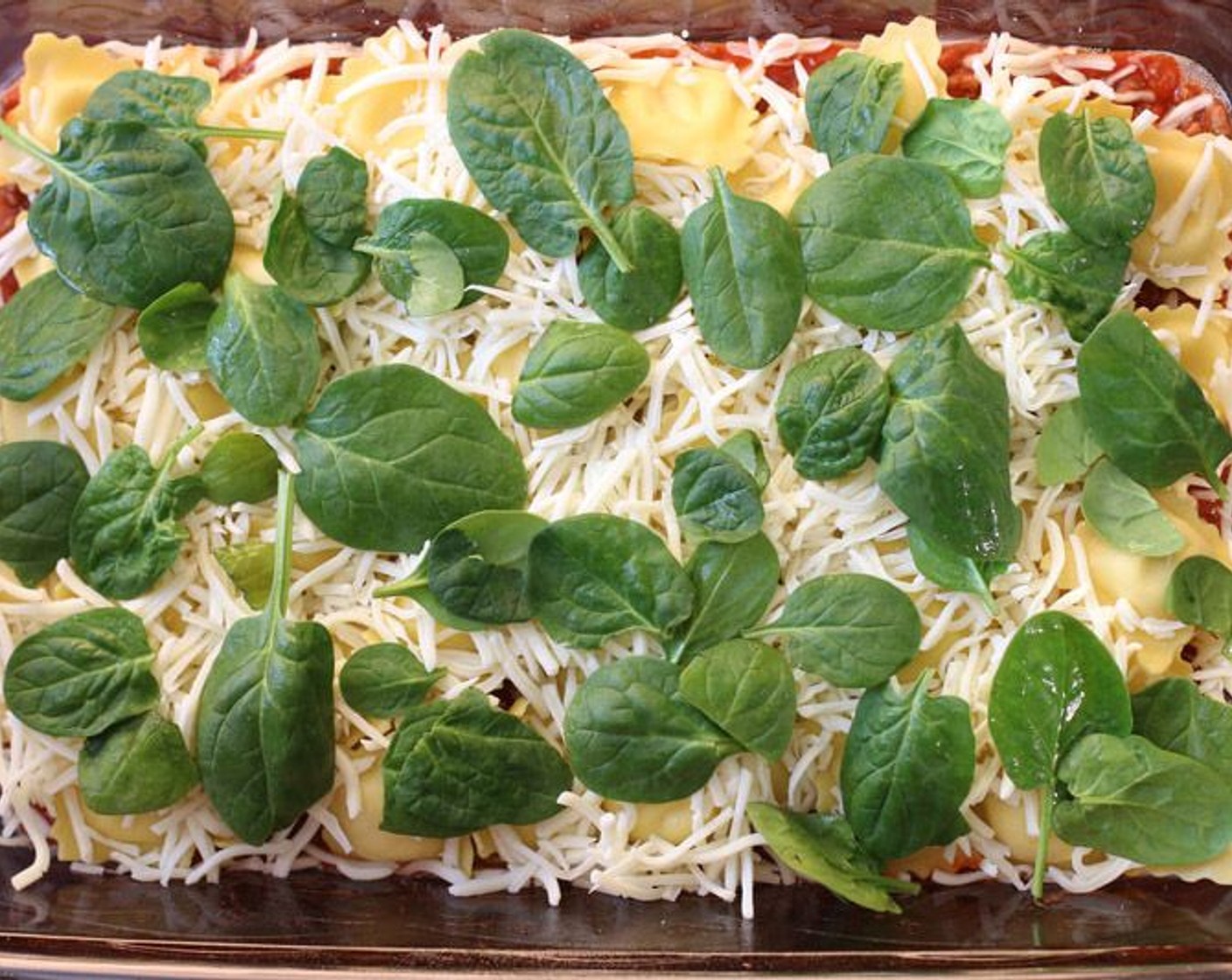 step 3 Spread 1/3 of meat sauce evenly across the bottom of the prepared pan. Arrange a single layer of Fresh Four-Cheese Ravioli (1 pckg), and then spread Shredded Mozzarella Cheese (1 1/2 cups) evenly over ravioli. Layer Fresh Baby Spinach (5 2/3 cups) over the cheese.