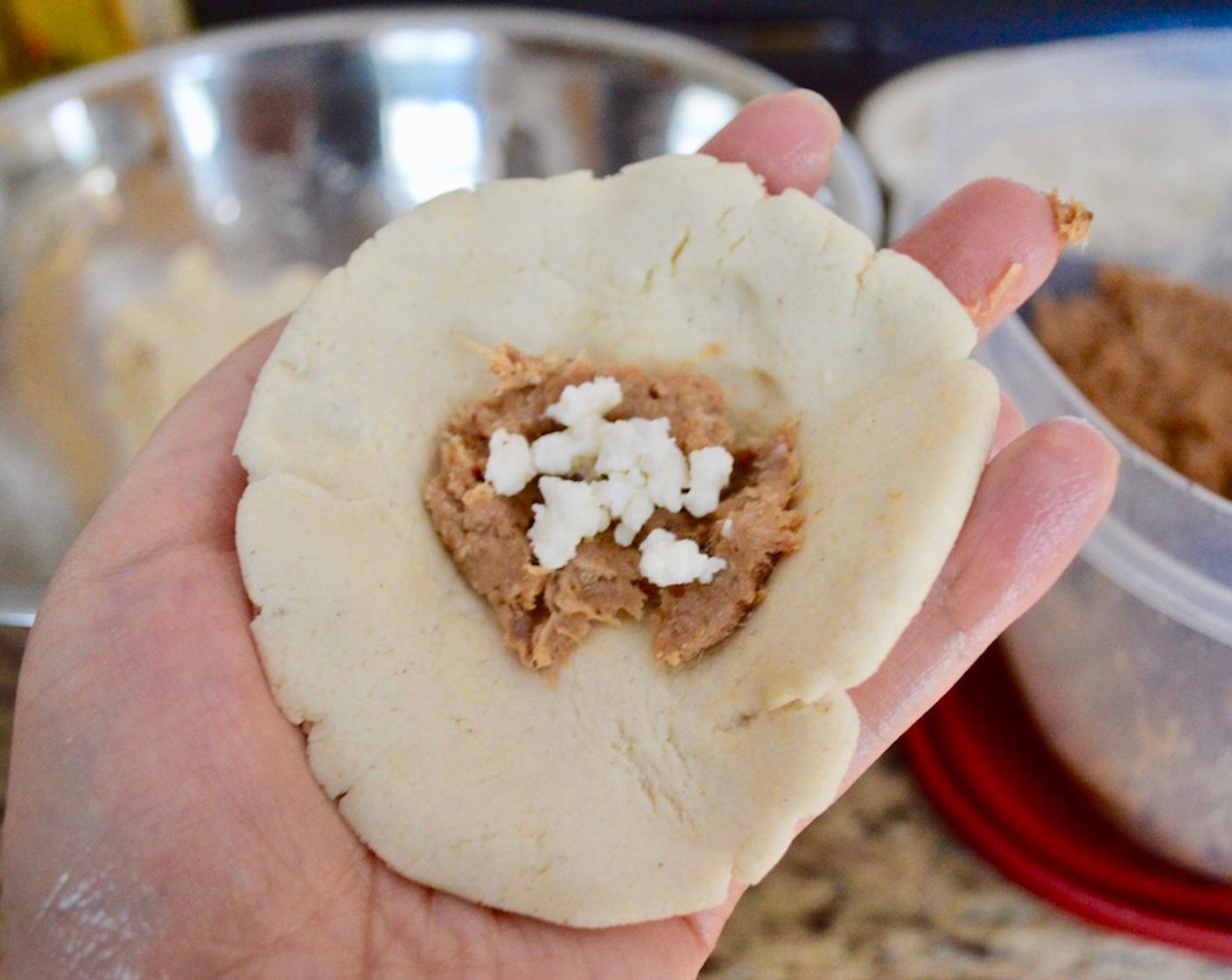 step 14 Then take a tablespoon of the pork filling and a pinch of the Queso Fresco (1 cup) and place it in the middle of the disc. Bring the edges over the filling almost like closing a dumpling. Since it will almost be like a little ball at this point, smooth out the ball in your hands and press it out again into a thin disc with the filling inside.