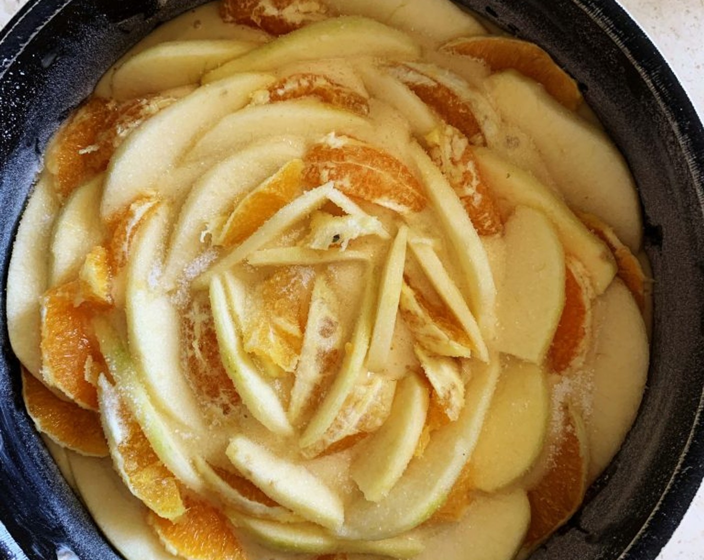 step 5 Oil and flour a 22-centimeter cake pan, pour in the batter, next thinly slice up the orange and an Apple (1), and lay them around alternating one slice of apple with one slice of orange.