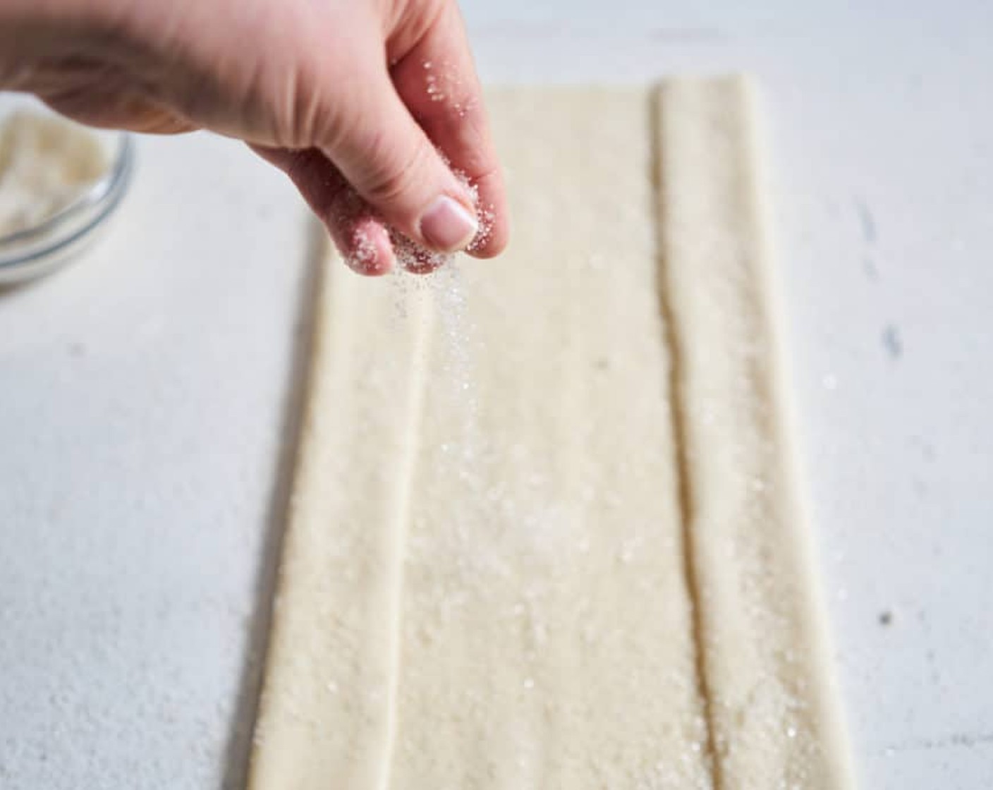 step 2 Fold the long sides of the pastry in ¼ of the way, then sprinkle with more sugar.