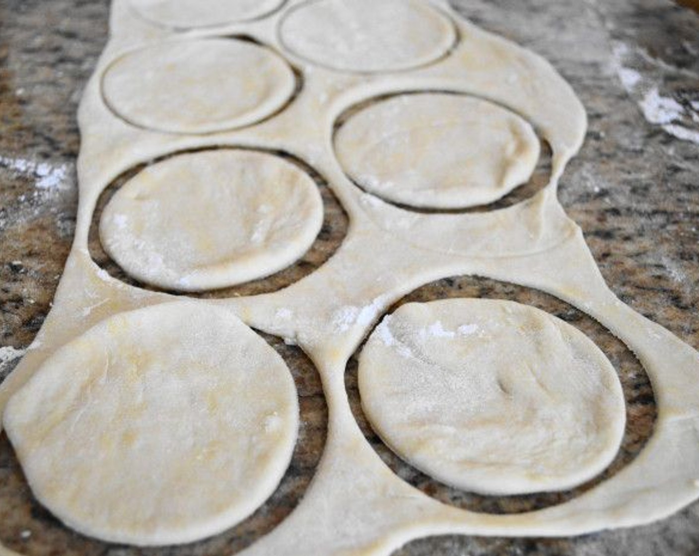 step 5 When the dough is done resting, divide it in half. Roll out the first half to about 1/4 inch thick on a floured surface with a floured rolling pin. With a 4 inch round cutter, cut out perfect little circles. You should get nine circles the first time.
