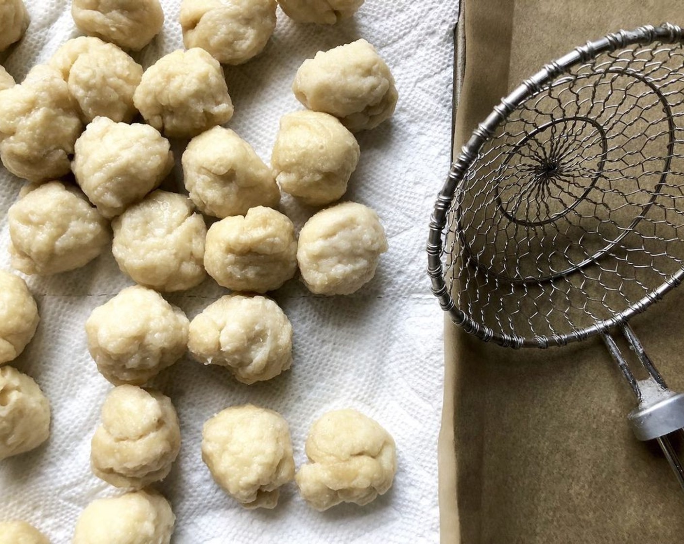 step 4 With a slotted spoon, remove the balls from the water and place them on paper toweling. Transfer them to the prepared baking sheet, spaced about 1/2-inch apart.