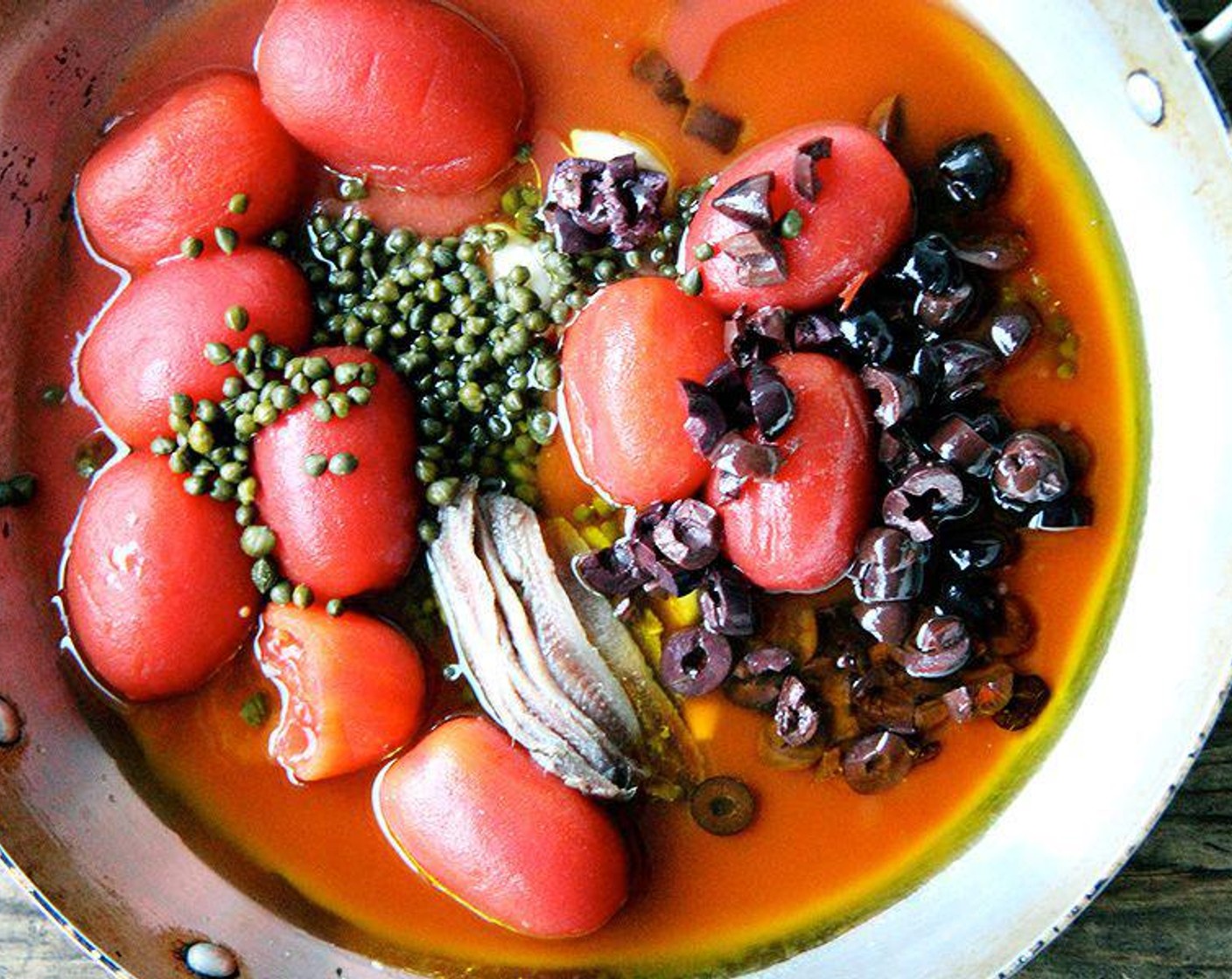 step 1 Place Extra-Virgin Olive Oil (1/2 cup), Anchovy Fillets (1 can), Garlic (4 cloves), San Marzano Tomatoes (1 can), Capers (4 Tbsp), Black Olives (1/2 cup), and Freshly Ground Black Pepper (to taste) in large pot or wide-mouthed sauté pan. Bring to a simmer over medium heat.