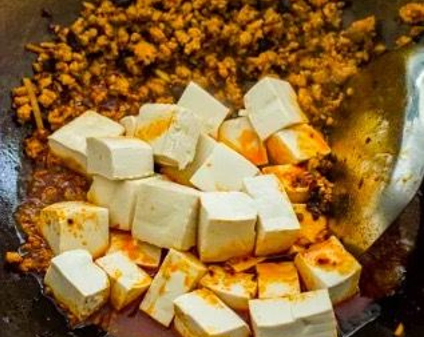 step 6 Push the ground pork towards the side of the wok, and add the Firm Tofu (1 block) to the wok. Reduce the heat to low and let it simmer for about 2 minutes. Stir occasionally and gently.