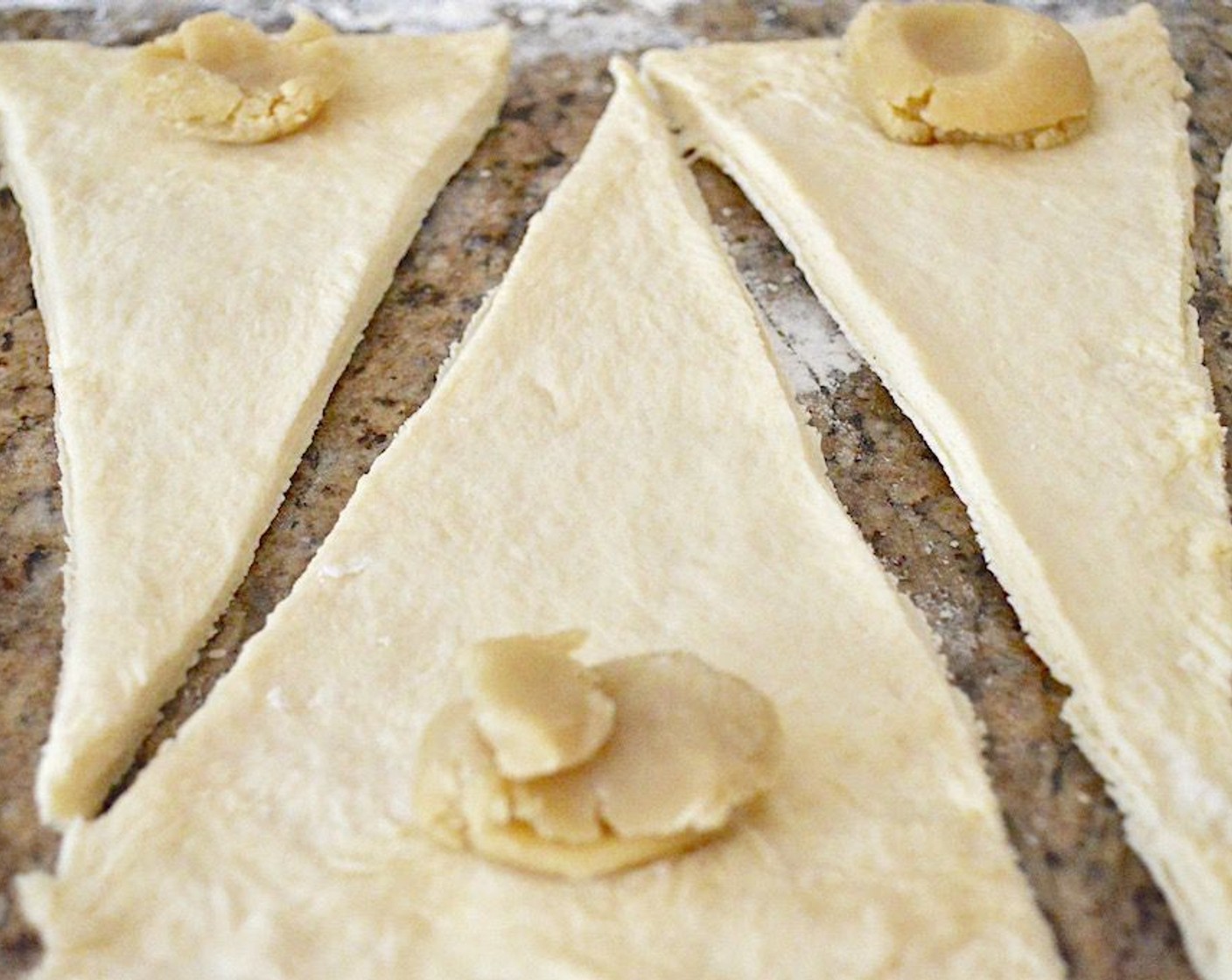 step 11 Place a tablespoon of Almond Paste (3/4 cup) at the wide base of each triangle. Then roll each one up tightly from the base to the pointy end, pulling gently on it as you roll it so that it is tightly rolled. Place them staggered on one of the baking sheets.