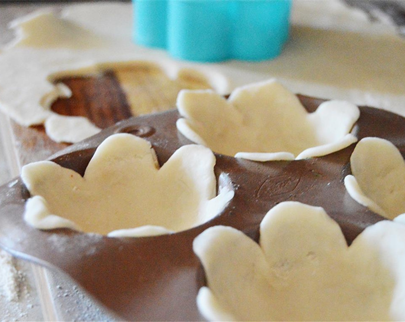 step 3 Use flower cookie cutter to cut out flowers. Press flowers into greased muffin tin cups.