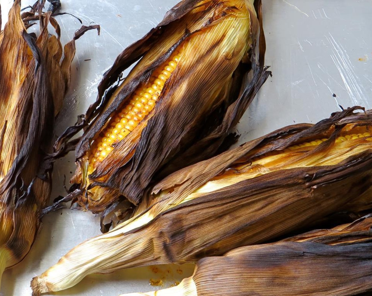 step 6 Transfer the corn to a baking sheet. Cool just until you can safely handle the corn without burning yourself. Fold the husks back away from the corn cob (or you can remove them, if you like.