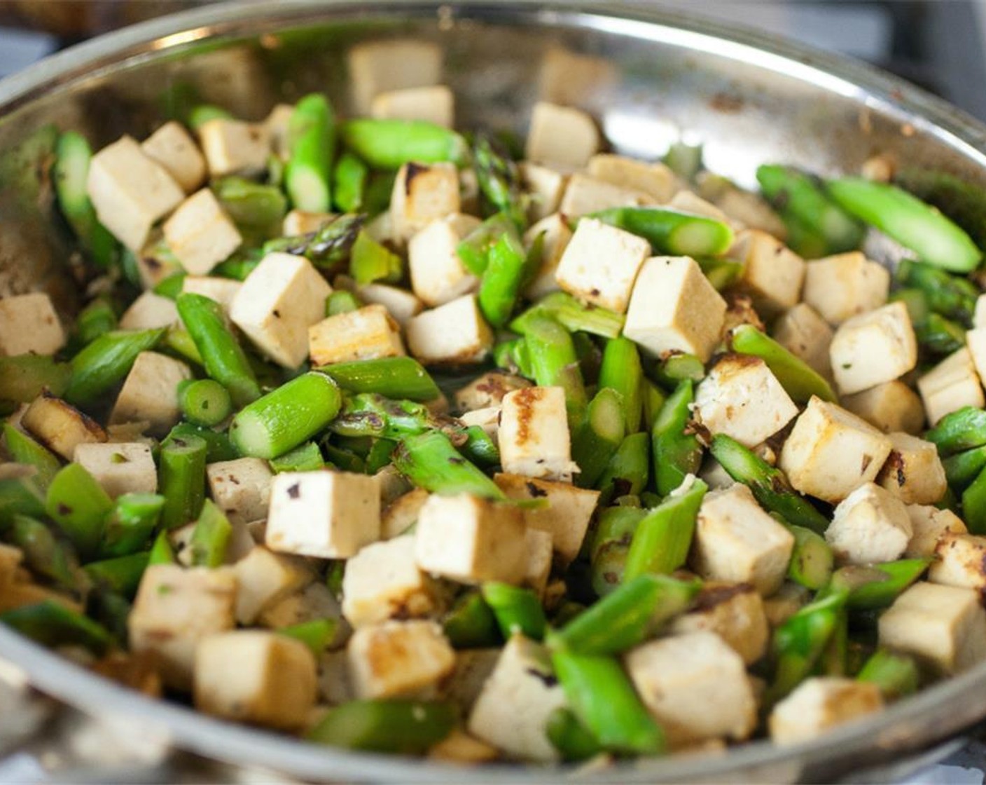 step 3 Meanwhile, in a large saute pan, heat Sesame Oil (1 tsp) over low heat. Towel off residual wetness from the cubed tofu and asparagus and add to pan with the remaining ginger and Brown Sugar (1 Tbsp).