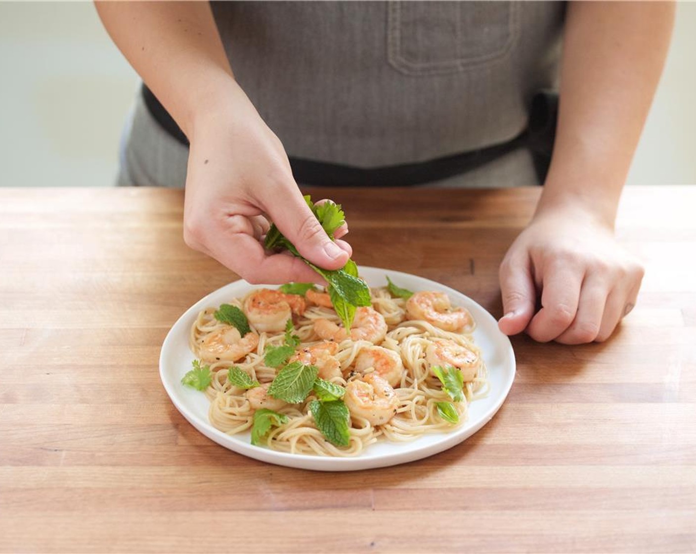 step 8 In the center of two plates, add the shrimp and vermicelli noodles. Garnish with fresh herbs. Serve with lime wedges on the side.