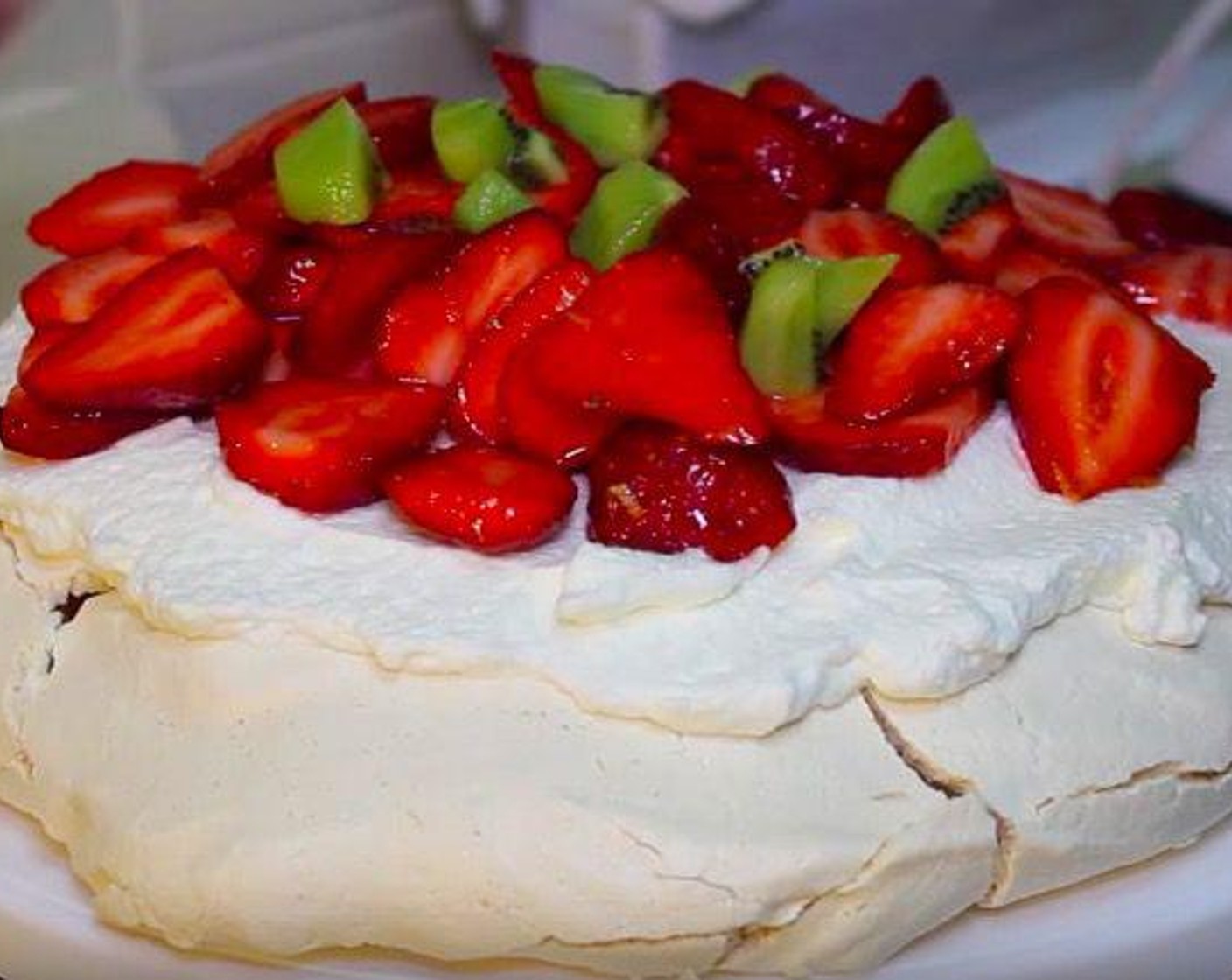 step 3 Put Heavy Cream (1 cup) and 2 tbsp of sugar into a beater and beat for 2 minutes to make whipped cream. Cut Kiwifruit (2) and Fresh Strawberries (3 cups). Transfer the strawberries on to a plate and mix it up with sugar and Orange (1). Put whipped cream on top of pavlola, followed by strawberries and kiwi.