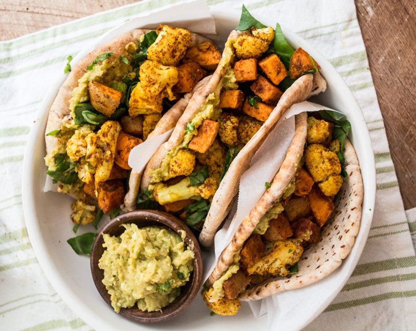 step 6 Once vegetables have cooked, add avocado hummus to pita or Naans (6 pieces) followed by Fresh Spinach (1 cup) then the cooked sweet potatoes and cauliflower, top with Cheese (to taste), if desired.