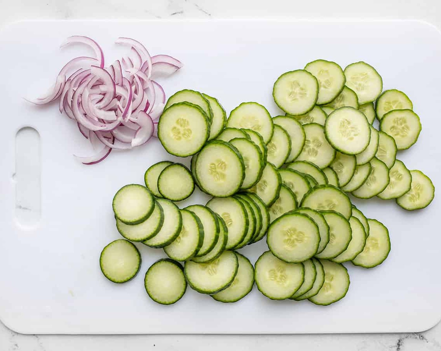 step 2 Peel the Cucumber (1), if desired. Slice the cucumbers and thinly slice the Red Onion (1/4).