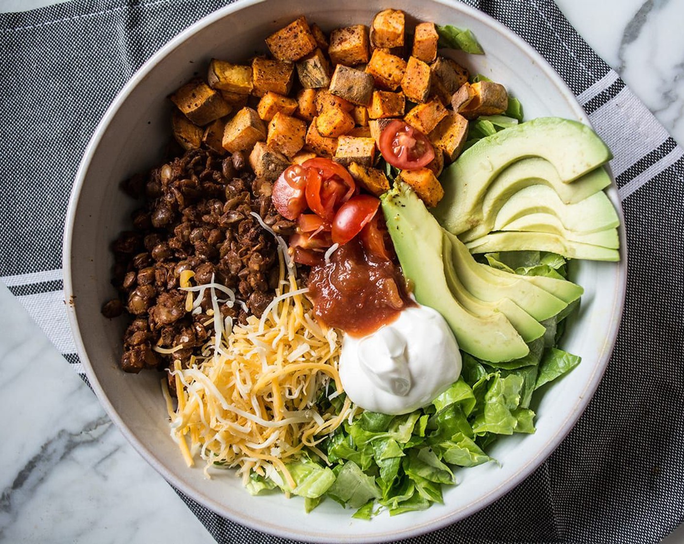 step 7 Begin by adding a layer of lettuce to the bottom of each bowl, then add half roasted sweet potatoes, half seasoned lentils, and top with your choice of Salsa (to taste), Shredded Cheese (1/4 cup), Sour Cream (to taste), Avocado (1), and Cherry Tomato (1/2 cup).