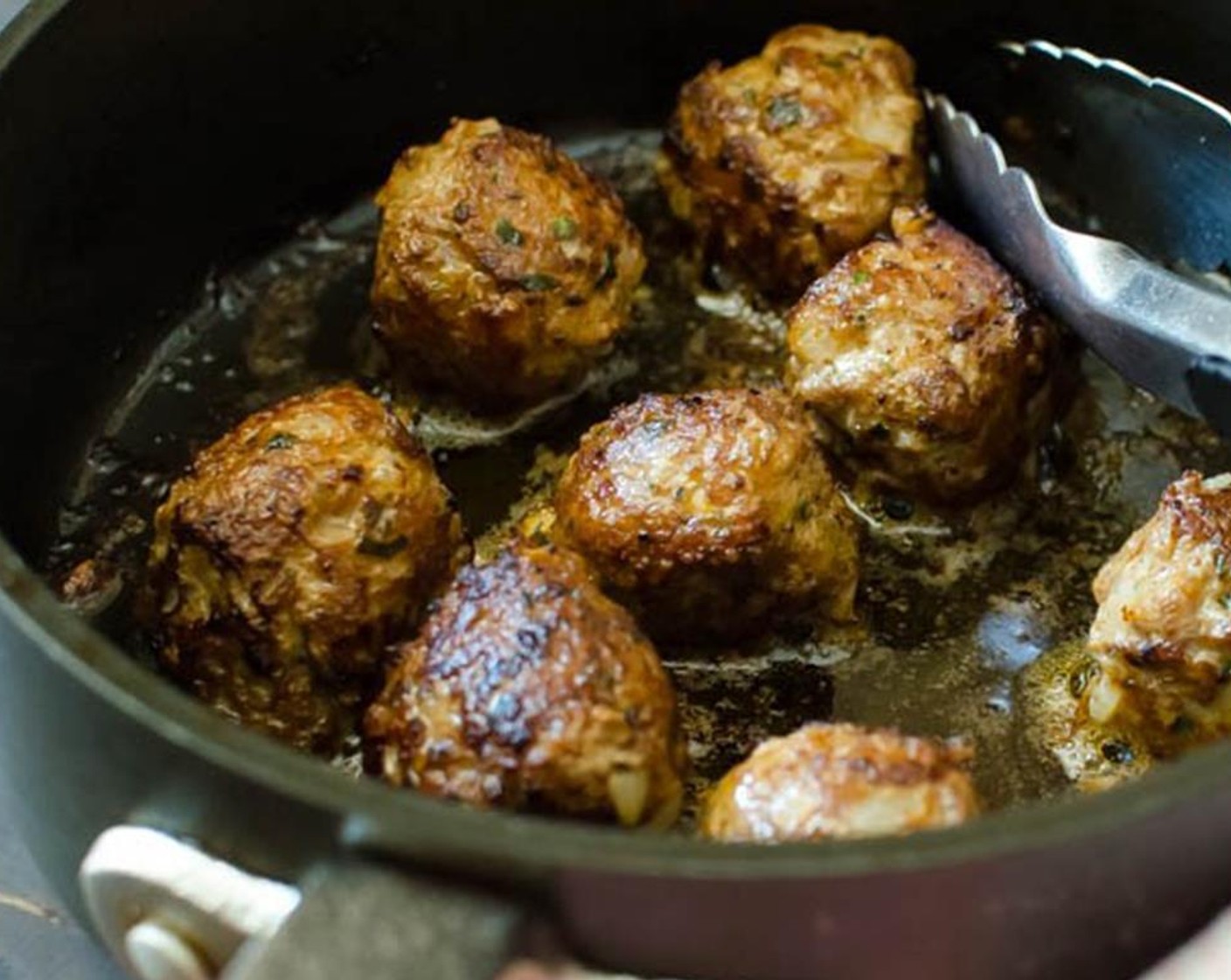step 3 Heat a heavy skillet over medium-high heat Canola Oil (as needed). Working in batches when oil is hot, add meatballs, cooking on all sides until browned and mostly cooked through. Transfer meatballs to a plate and set them aside.