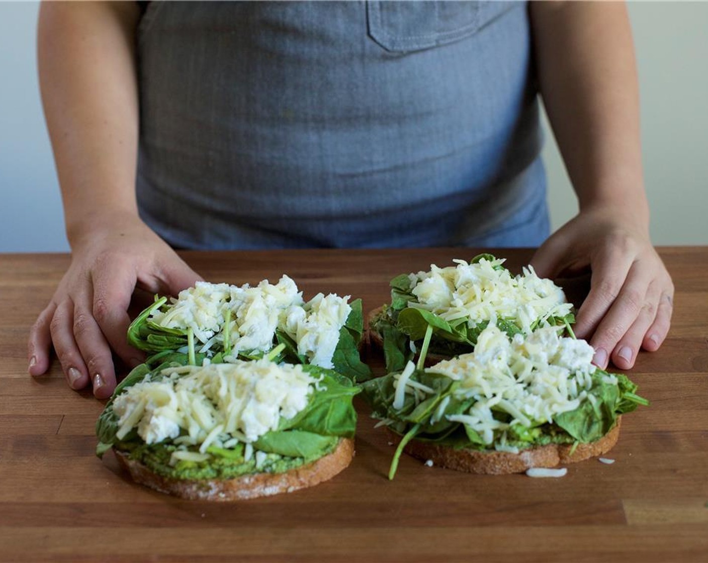 step 7 Place the Fresh Baby Spinach (115 g), Goat Cheese (115 g), Mozzarella Cheese (115 g) and toss over each slice of bread. Turn the heat up on the saute pan to medium, and add Butter (4 Tbsp) to the pan.