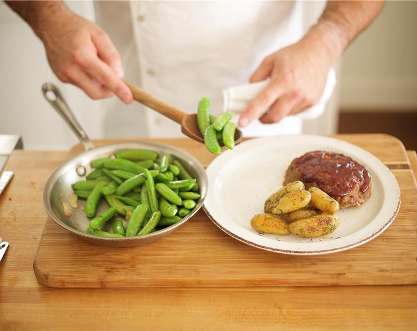 step 11 Divide the sugar snap peas and potatoes onto two plates. Position the meatloaves alongside the potatoes and snap peas.