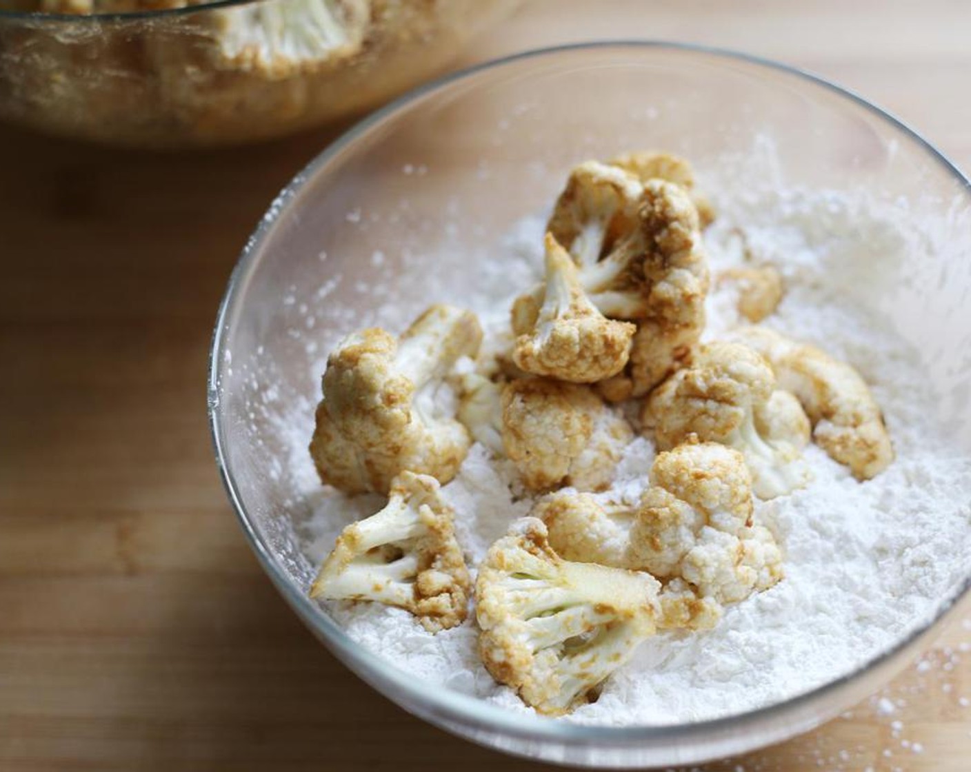 step 6 In a separate bowl, add the Corn Flour (2 cups) add the cauliflower florets in batches and toss.