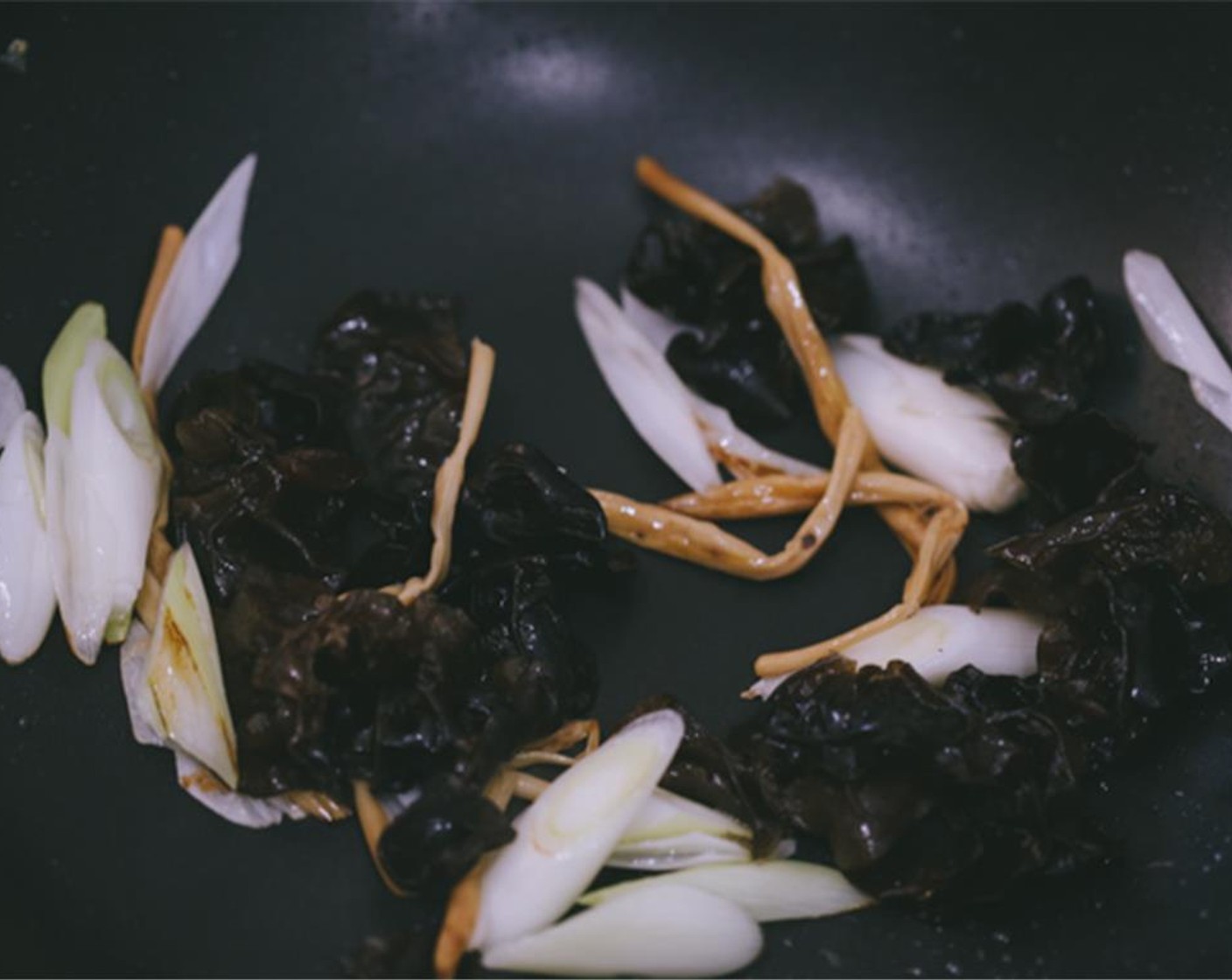 step 6 Leave around 1 tablespoon of oil in the wok and then fry the Garlic (1 clove) until fragrant, place prepared Wood Ear Mushrooms (1 handful), Daylily (1 bunch), and carrot. Continue frying for around 1 minute over medium heat.