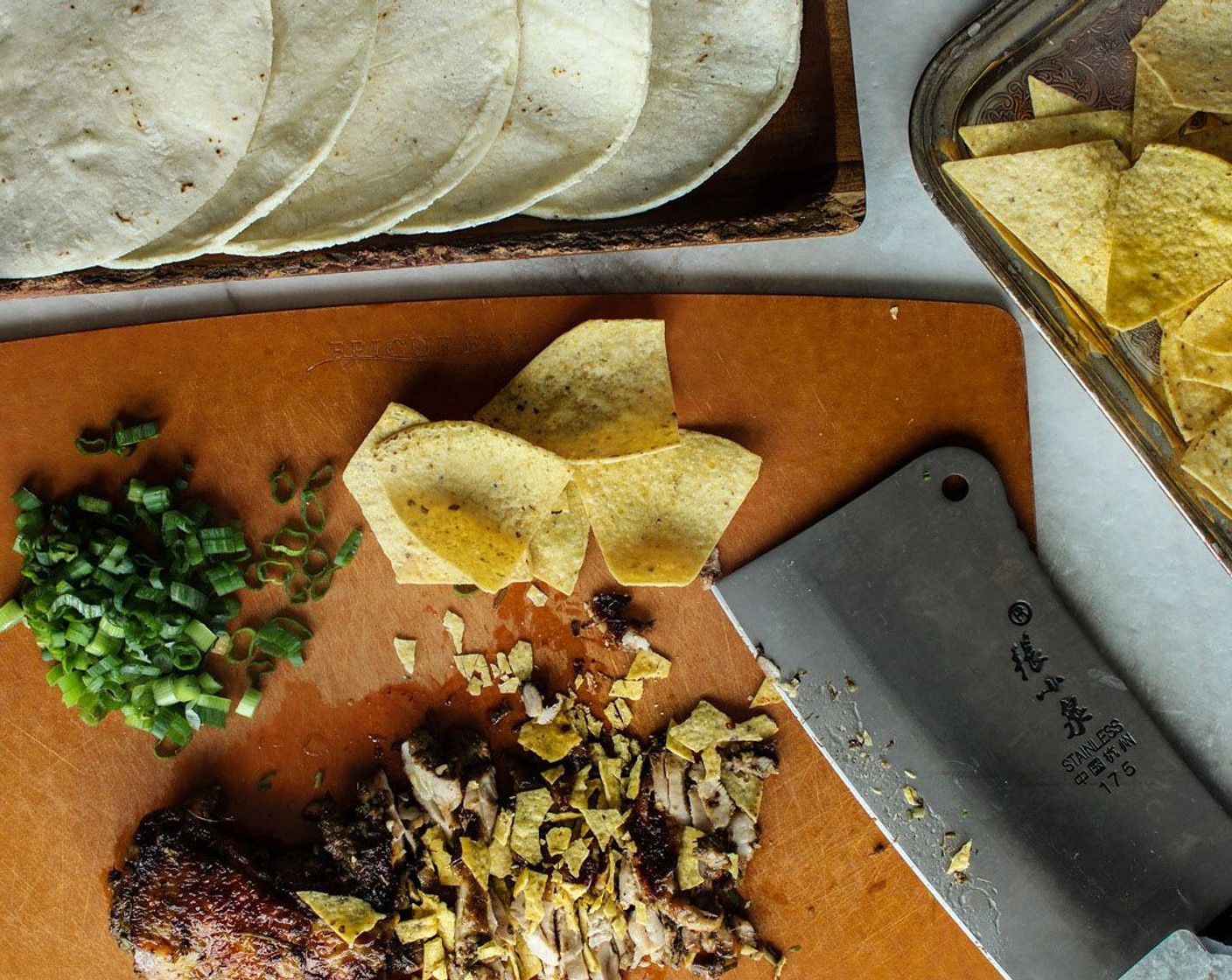 step 4 Once the chicken is done, transfer it to a cutting board and place some Tortilla Chips (1 handful) on top of the chicken and chop it up together. Mix in the Scallion (1 stalk).