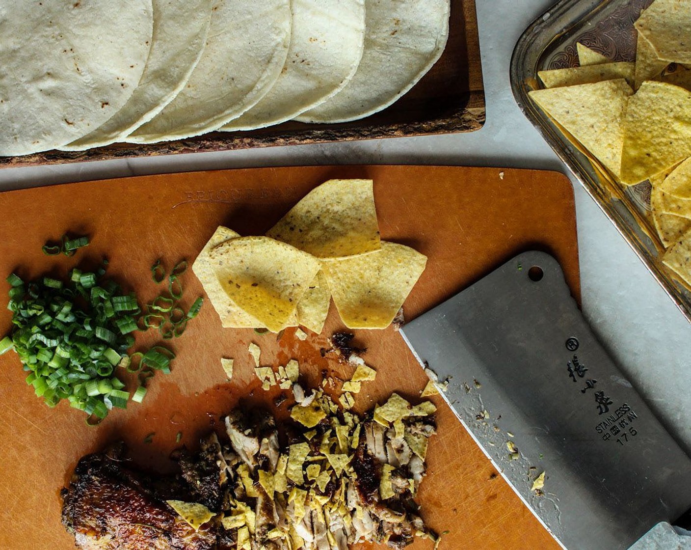 step 4 Once the chicken is done, transfer it to a cutting board and place some Tortilla Chips (1 handful) on top of the chicken and chop it up together. Mix in the Scallion (1 stalk).