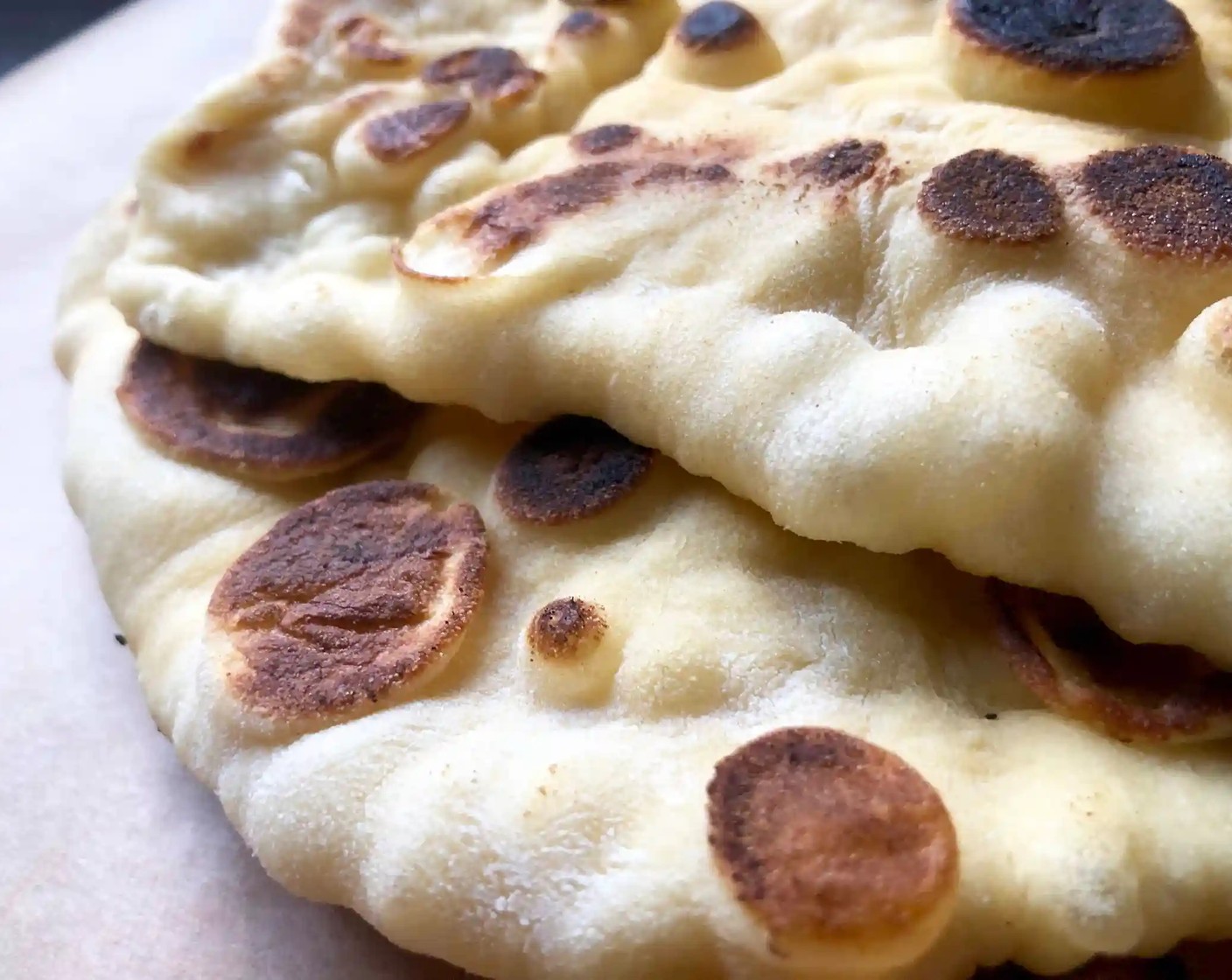 step 12 Flip the naan and cook, uncovered for another minute or so until multiple toasted spots appear on the underside. As you work, keep the stack of cooked naan wrapped in a linen towel.