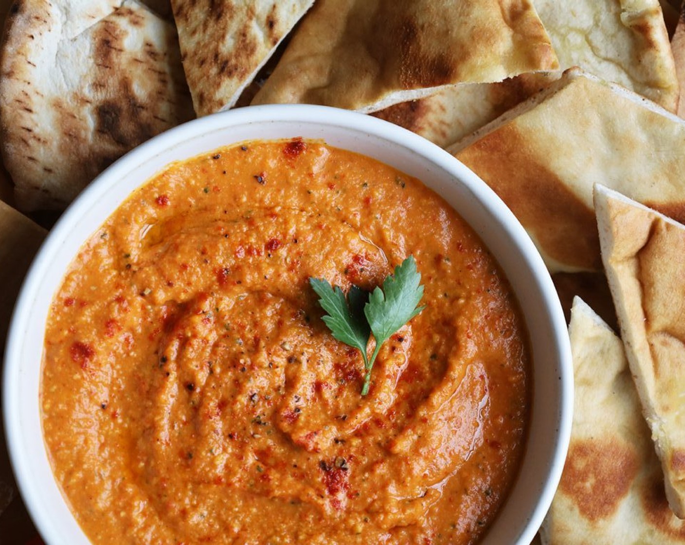 step 7 Spoon the hummus into a serving bowl, garnish with a swirl of olive oil, a pinch of paprika, and a sprig of parsley, and serve with Crudites (to taste) and Pita Bread (to taste) for dipping.