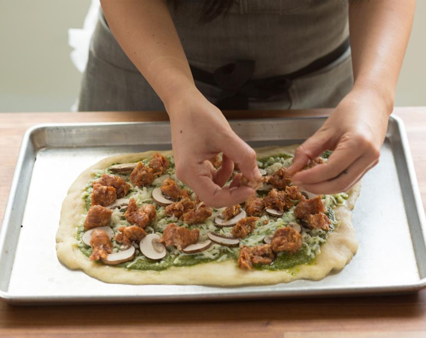 step 7 Spread only HALF of the Basil Pesto (1/3 cup) over the pizza, leaving about a 1-inch border around the edges of the dough. Spread the shredded Mozzarella Cheese (1 cup) and top with the sliced mushrooms and sausage pieces.