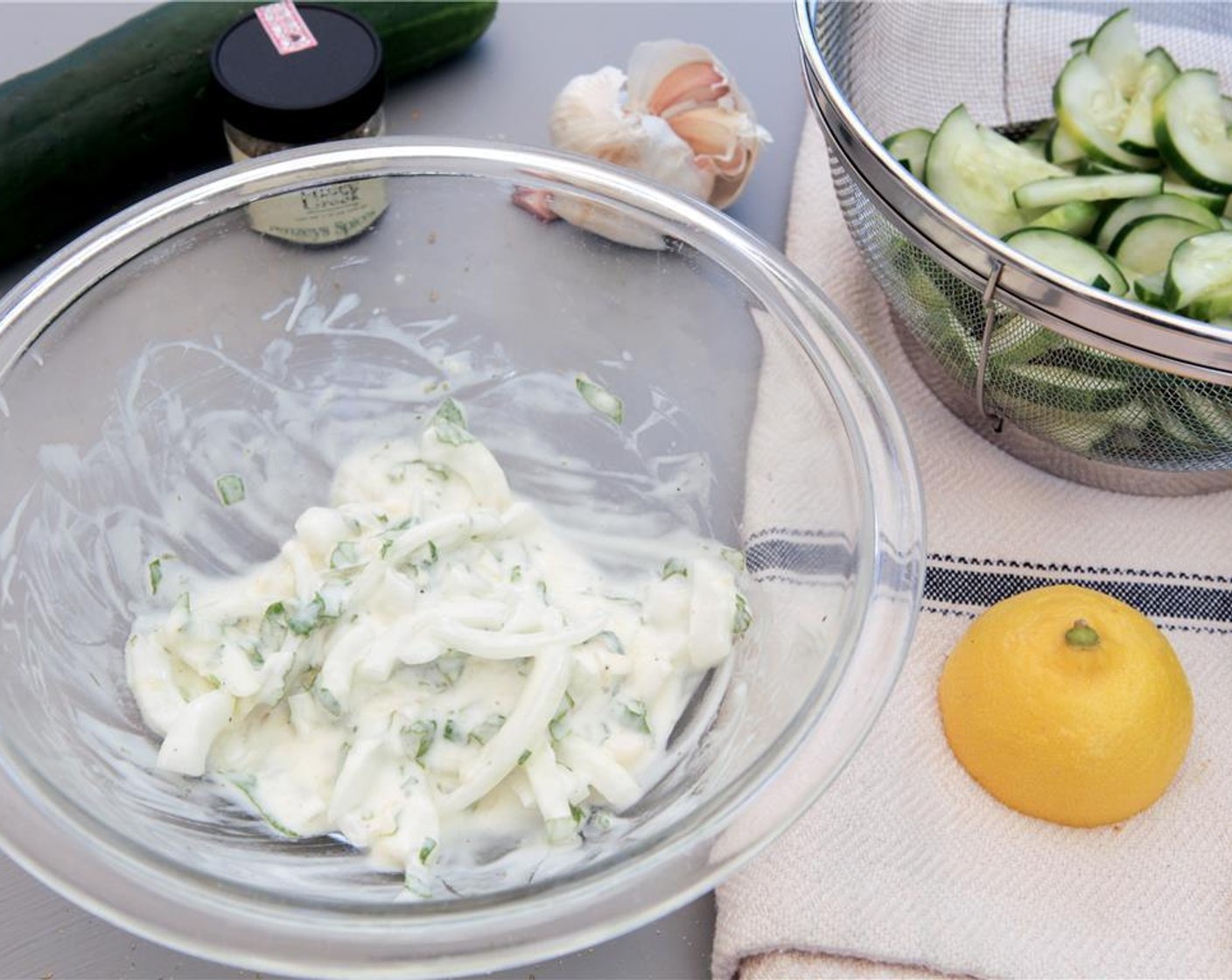 step 6 While you wait on the cucumbers, juice the remaining half of the lemon into a medium bowl and combine with the chopped mint, minced garlic, remaining sliced onion and Plain Greek Yogurt (1/4 cup).
