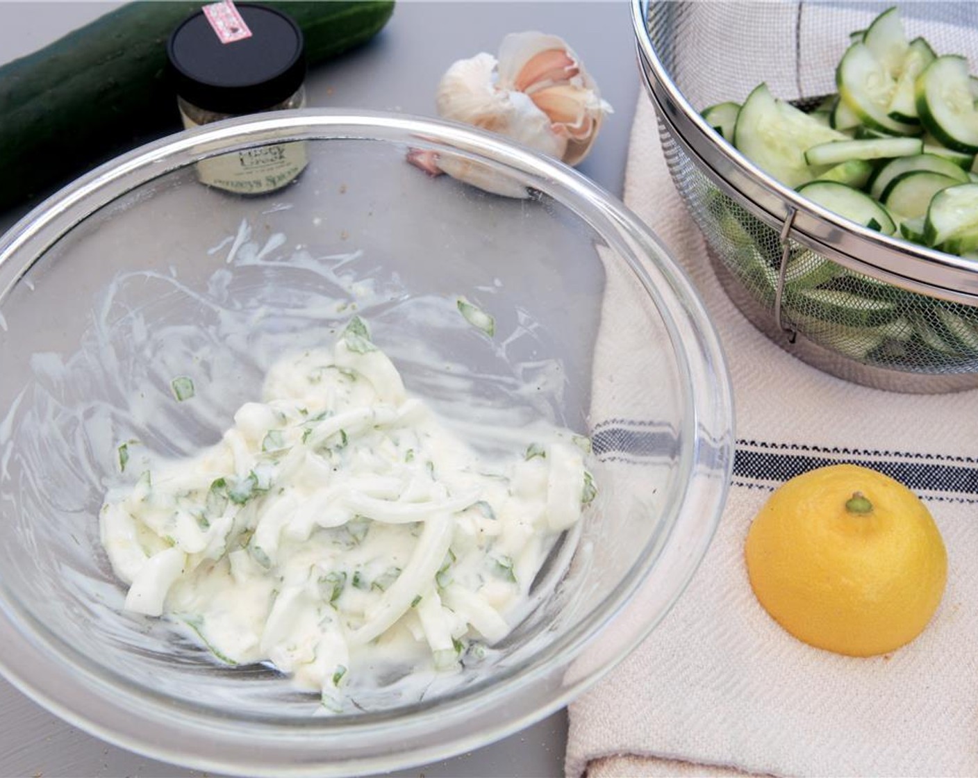 step 6 While you wait on the cucumbers, juice the remaining half of the lemon into a medium bowl and combine with the chopped mint, minced garlic, remaining sliced onion and Plain Greek Yogurt (4 Tbsp).