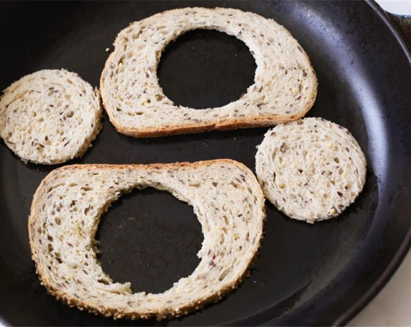 step 3 Heat a large skillet (preferably cast iron) over medium-high heat. When hot, add the Olive Oil (1 tsp) and swirl to coat the bottom of the pan. Add the bread slices and rounds to the pan and cook for about 3 minutes until the undersides are golden brown.