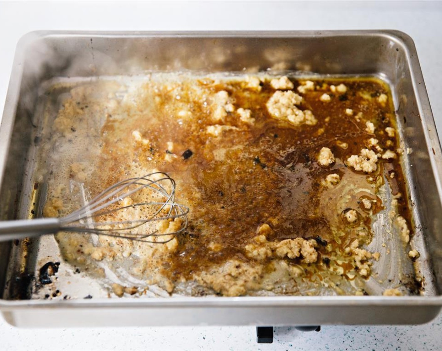 step 6 Continue cooking over low heat, scraping the bottom of the roasting tray with the whisk. The mixture will begin to brown as it cooks.