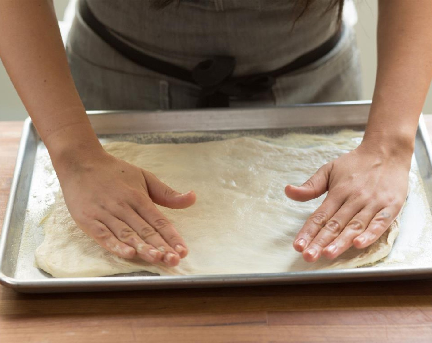 step 4 Sprinkle the Semolina Flour (2 Tbsp) onto a sheet pan to cover. Rub a little Olive Oil (as needed) on your hands to prevent sticking, and gently shape the Pizza Dough (1) into a rectangle. Stretch the dough into a 1/4 inch thickness.