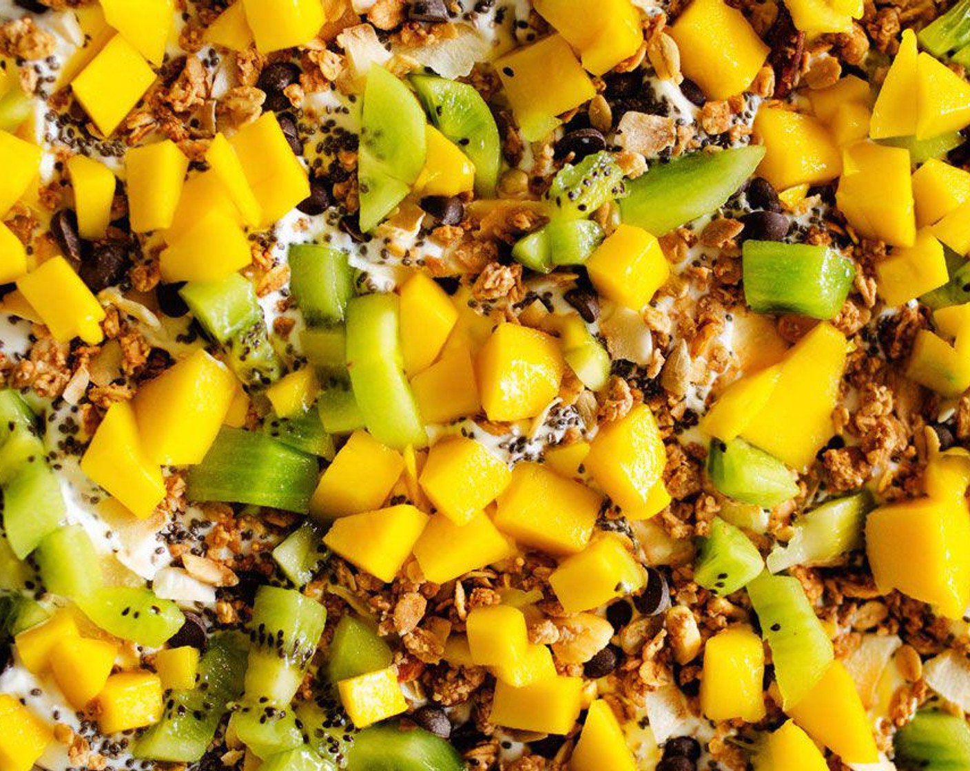 step 2 Sprinkle Granola (4 Tbsp), Kiwifruit (2), Mango (1), Unsweetened Shredded Coconut (2 Tbsp), Chocolate Chips (1 Tbsp), and Chia Seeds (1 tsp) onto yogurt, pressing down with a spoon or spatula to ensure all the toppings are touching the yogurt.