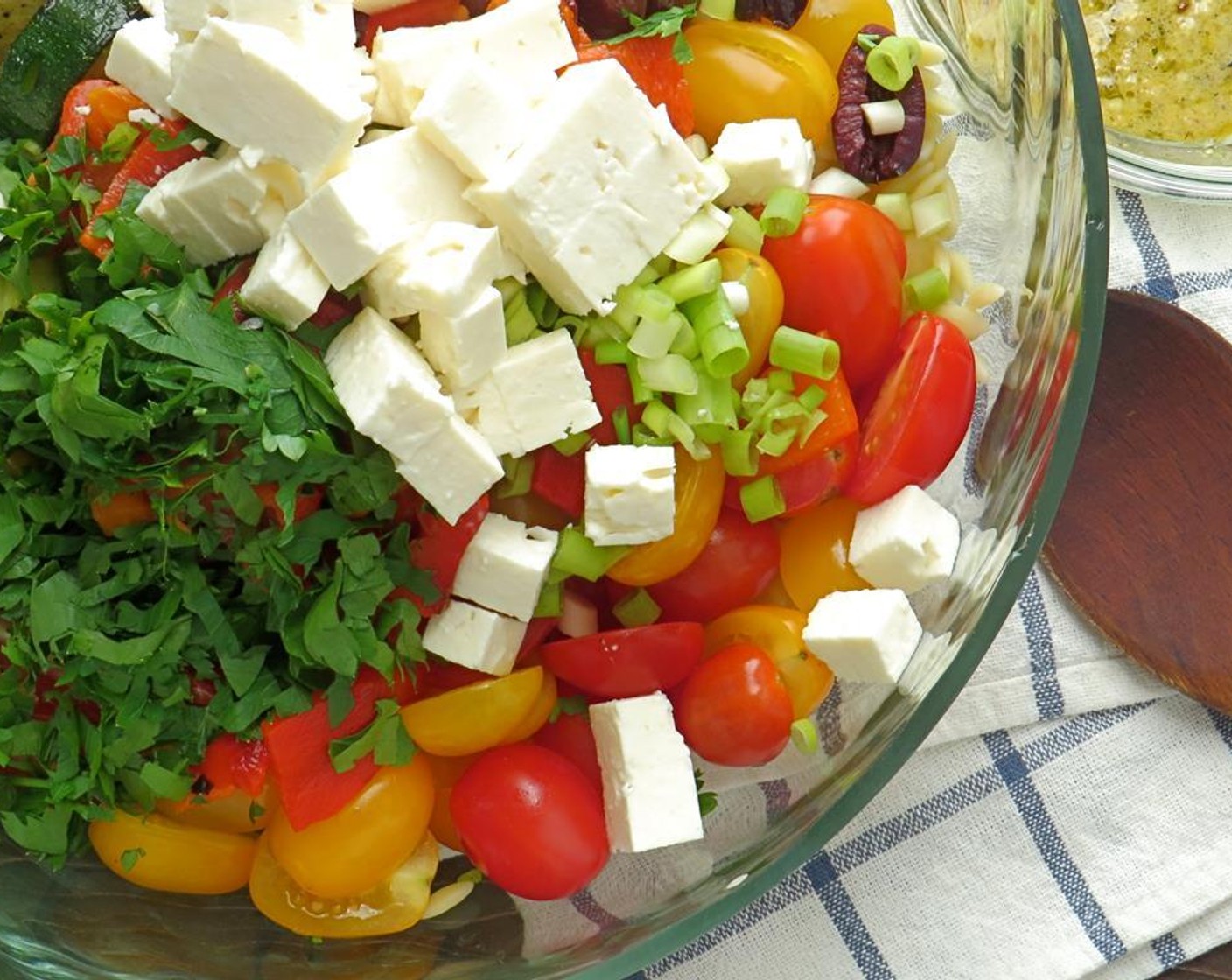 step 16 In a large bowl, combine, orzo, red pepper, zucchini, onion, olives, tomatoes, green onions, parsley and feta cheese. Toss to combine.