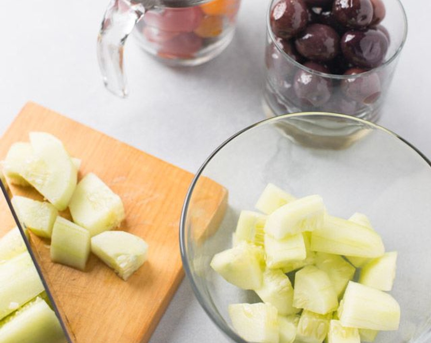 step 1 Peel and cut Cucumbers (1 1/2 cups) into bite-sized cubes. Cut Cherry Tomato (1 cup) and Pitted Spanish Black Olives (3/4 cup) in halves. Place in a large mixing bowl.