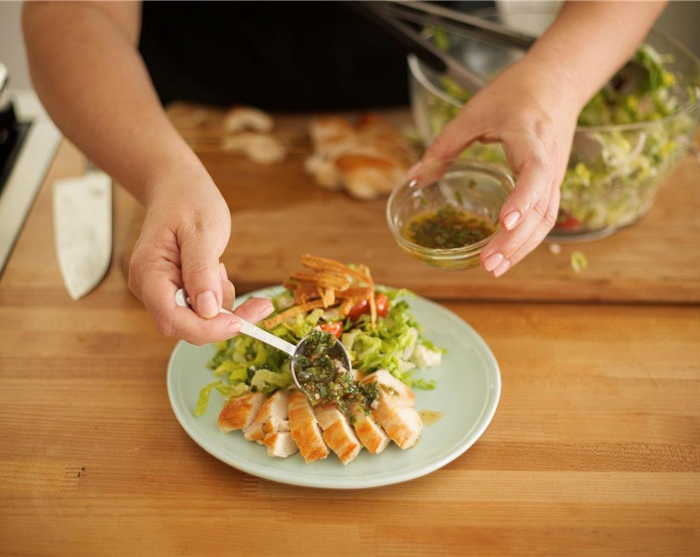 step 11 Gently toss the salad and divide evenly between two plates behind sliced chicken. Plate salad with height, being sure to showcase all ingredients. Top each salad with crispy pita crisps. Drizzle remaining dressing over sliced chicken on both plates