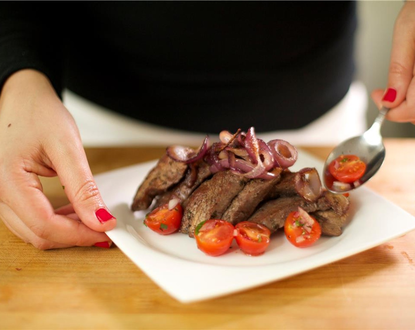 step 8 Divide the flank steak evenly between two plates. Arrange the cherry tomato salad around the slices of steak. Place the caramelized onions on top. Your dinner awaits!