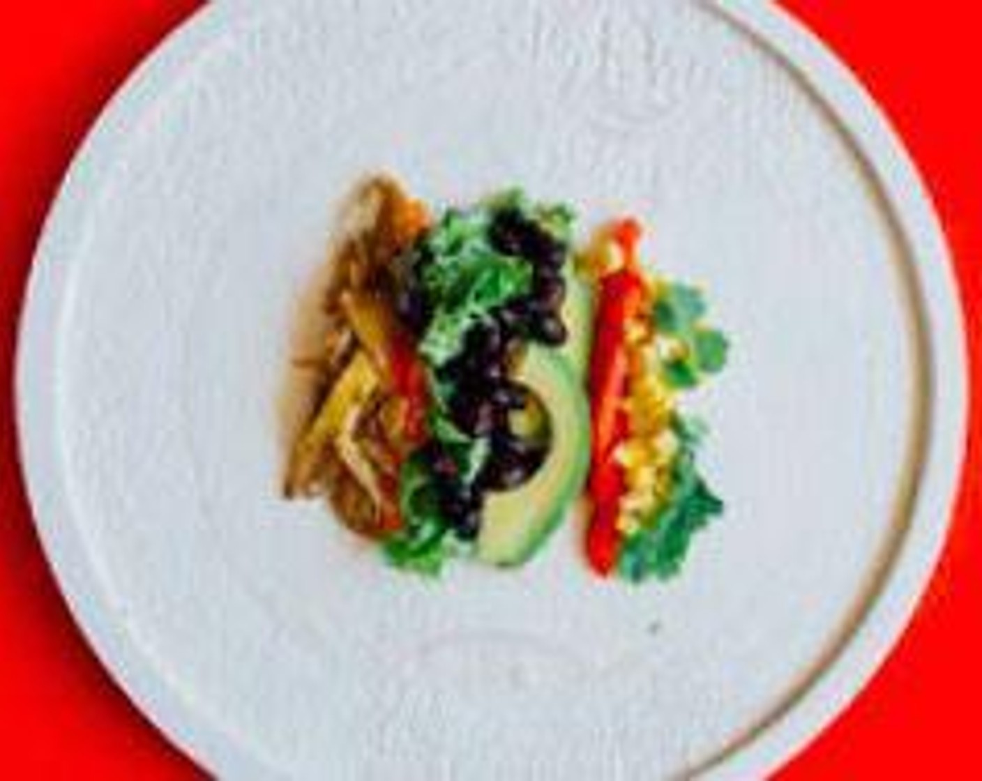 step 4 Stack mushrooms, Corn (1 ear), GOYA® Black Beans (2 1/3 cups), Red Bell Pepper (1), Avocado (1), Carrots (3), Fresh Cilantro (1/2 cup), and Lettuce (1 cup) on the rice paper in a row, leaving about 2 inches on either side.