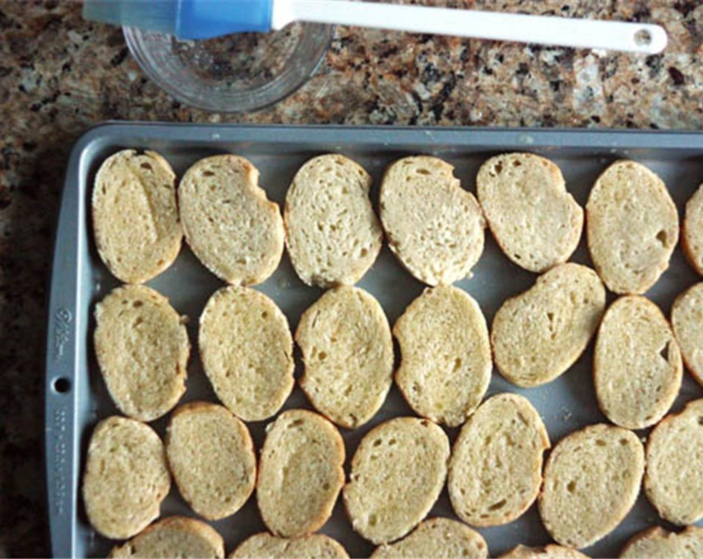 step 5 Place an oven rack in the center of the oven and preheat the broiler on high. Slice the Baguette (1/2) and spread the slices on a cookie sheet in a single layer. Melt the Unsalted Butter (1/4 cup) and brush lightly over each piece of bread.