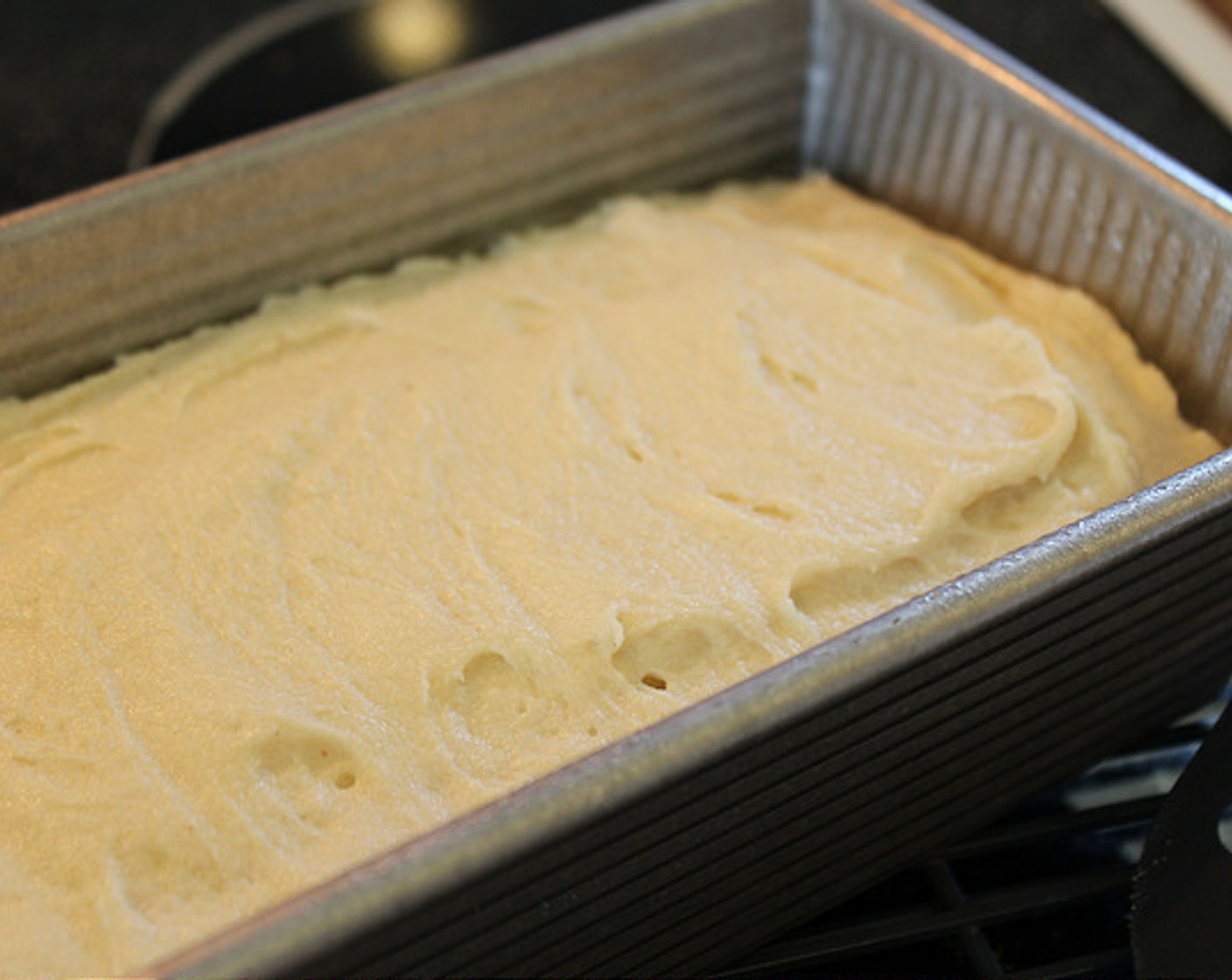 step 7 Using a spatula, scrape the bread mixture into your prepared loaf pan and set on top of your stove to proof while the oven is preheating. Be sure to smooth out the loaf with spatula or wet fingers before proofing as the loaf will not smooth out itself.
