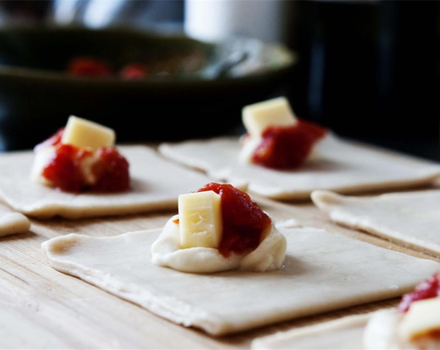 step 5 Lay out the Puff Pastry (20). Right in the center of each puff pastry sheet, place 1 tsp of Bechamel sauce, 1 small piece of tomato, and 1 cube of mozzarella cheese.