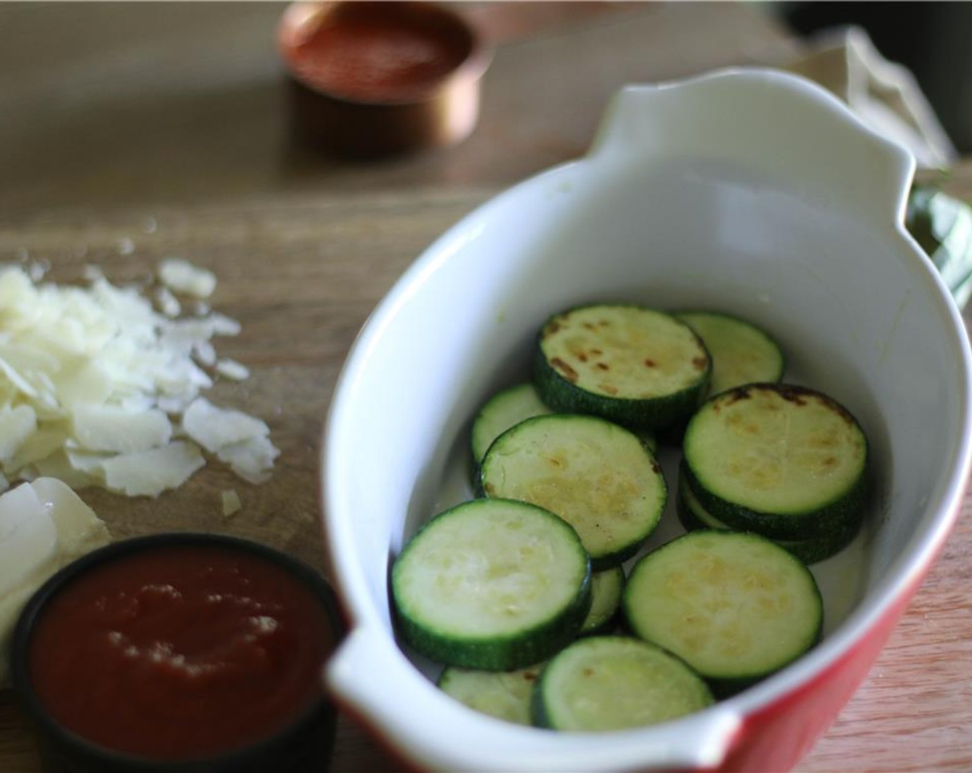 step 3 In a small baking dish arrange as many zucchini slices that can fit in a layer, top with a layer of Tomato Sauce (1 cup), a few pieces of Mozzarella Cheese (1 cup) a bit of Fresh Basil Leaves (to taste) and sprinkles of Parmesan Cheese (1 cup). Reserve some of the Parmesan for the main dish.