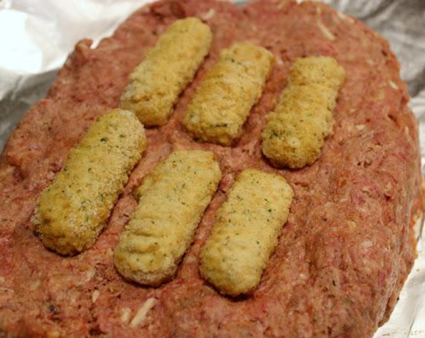 step 4 Spray a large piece of foil with cooking spray.  Flatten out meatloaf into a 9" x 6" rectangle. Arrange mozzarella sticks side by side. Form into a loaf shape enclosing mozzarella sticks. Place in 8 x 12 baking dish. Bake for 30 minutes.