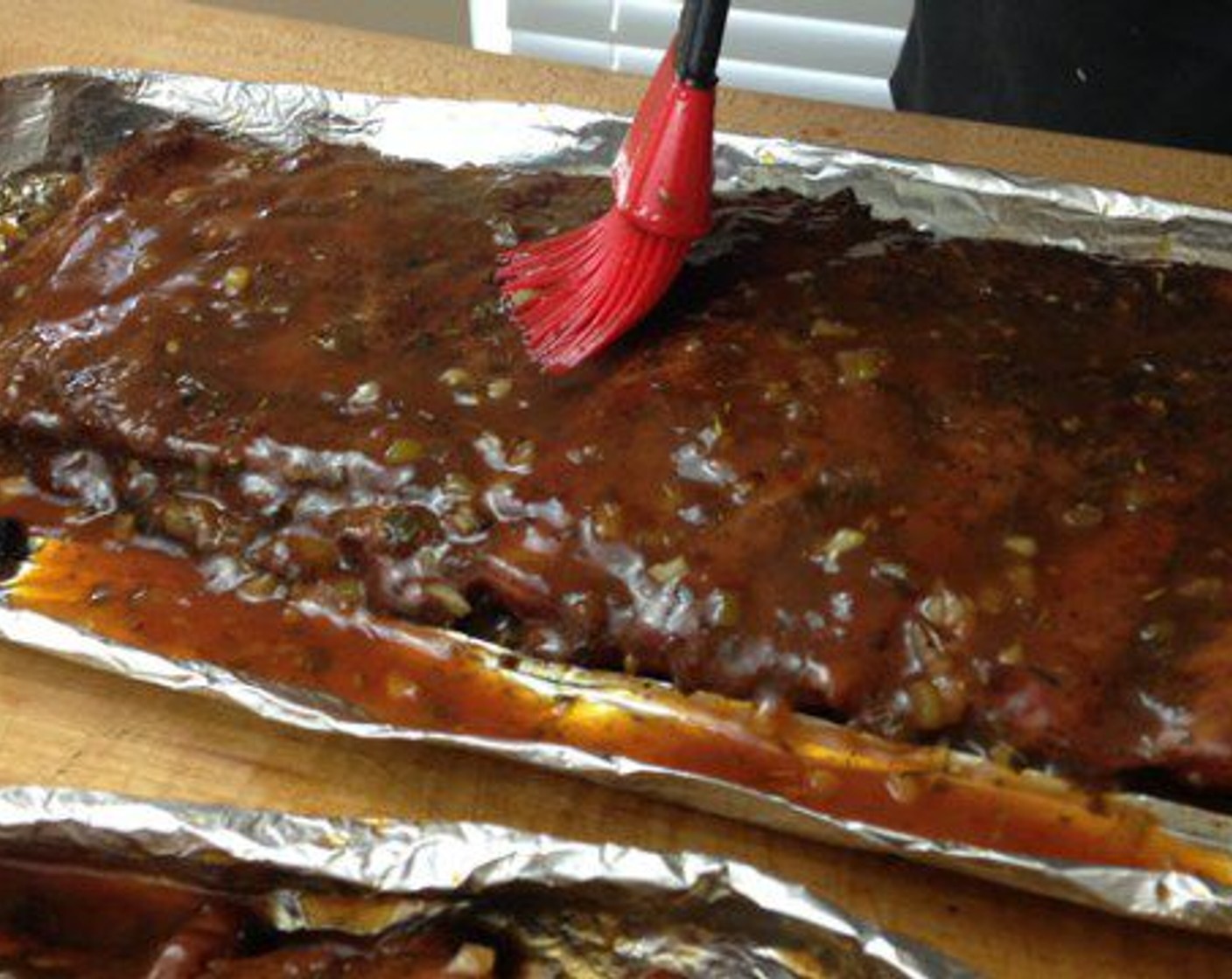 step 10 Now that the Jerk Style Spare Ribs are tender, bring both racks inside and carefully drain the liquid out of the foil. Fold the foil into a tray/boat shape around the ribs. This step makes it easier to transfer the ribs back to the smoker for a final glaze.